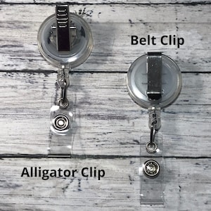 May include: Two clear retractable badge holders with different clip styles. One has an alligator clip, and the other has a belt clip. The text "Alligator Clip" and "Belt Clip" are visible.