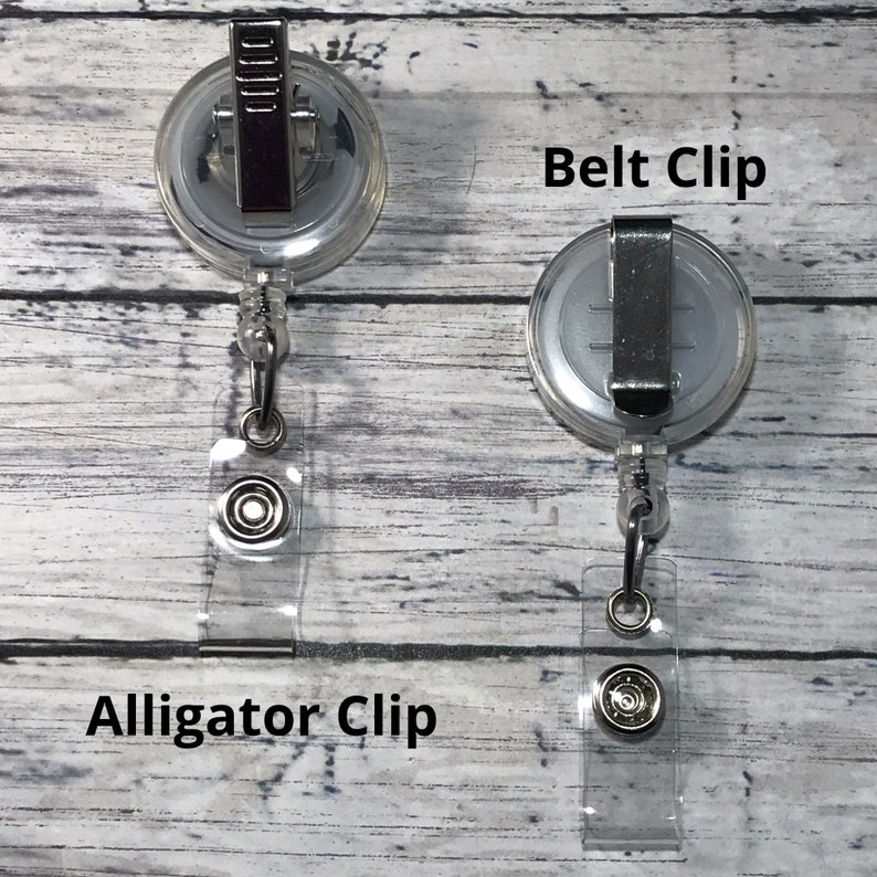 May include: Two clear retractable badge holders with different clip styles. One has an alligator clip, and the other has a belt clip. The text "Alligator Clip" and "Belt Clip" are visible.