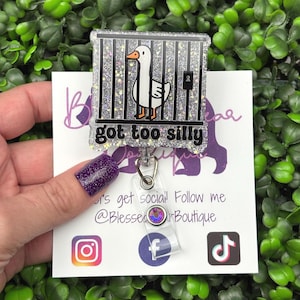 The badge reel features a cartoon white goose behind black prison bars, with the text "got too silly" in white letters on a black background below the bars. The badge reel has a clear plastic retractable cord and a snap closure, with a small, iridescent gemstone attached near the bottom.