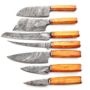 Può includere: Set di sette coltelli da cucina con manici in legno. Le lame sono in acciaio damascato e hanno un motivo ondulato.