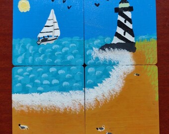 May include: Four wooden coasters with a nautical theme. The top two coasters feature a sailboat and a lighthouse on a blue ocean background. The bottom two coasters show a white wave crashing on a sandy beach.