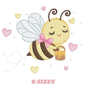 Könnte beinhalten: Gesticktes Design einer Cartoon-Biene mit geschlossenen Augen, die eine rosa Schleife trägt und einen Honigtopf trägt. Die Biene ist von Herzen und dem Text "6 SIZES" in Rosa umgeben.
