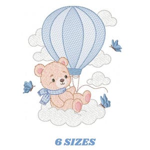 Op de afbeelding: Geborduurd ontwerp met een teddybeer in een luchtballon, omringd door wolken en vlinders. De beer draagt een blauwe sjaal. De tekst "6 SIZES" staat eronder.