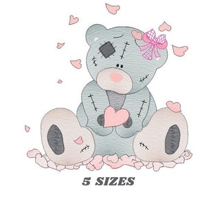 Può includere: Un orsacchiotto di peluche grigio con toppe e dettagli rosa è seduto su un letto di cuori rosa. L'orso tiene un cuore rosa nelle sue zampe. L'orso ha un fiocco rosa sulla testa. Il testo "5 SIZES" è sotto l'orso.