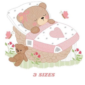 Può includere: Disegno ricamato di un orso bruno che dorme in un cesto rosa e bianco con un cuore sulla coperta. Un piccolo orso di peluche marrone è seduto sull'erba sotto. Il disegno include farfalle e fiori rosa. Il testo "3 SIZES" è in fondo all'immagine.