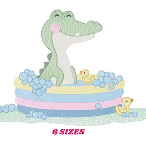 Może przedstawiać: Zielony aligator z różowym rumieńcem siedzi w niebieskim, różowym i żółtym dmuchanym basenie z dwoma żółtymi gumowymi kaczkami. Wokół basenu i na zielonej trawie są niebieskie bąbelki.