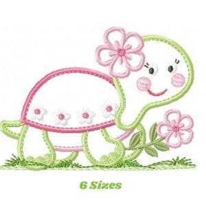 May include: Embroidered design of a green turtle with a pink flower on its head and a pink flower in its hand. The turtle is walking on green grass. The design is available in 6 sizes.