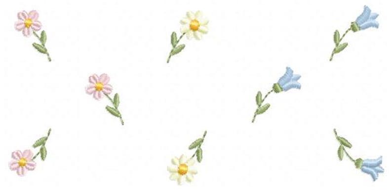 May include: Embroidered floral design featuring scattered flowers in pink, white, and light blue. Each flower has a yellow center and green stem with leaves. The design is on a white background.