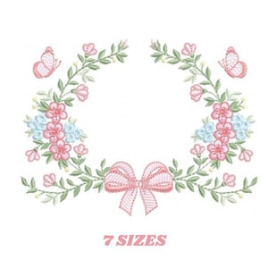 May include: Embroidered floral design featuring pink flowers, blue accents, and green leaves arranged in a wreath shape. Two butterflies and a bow are included. The text "7 SIZES" is displayed in pink.