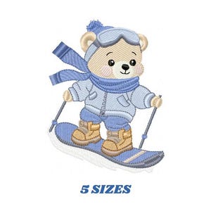 Peut inclure: Broderie représentant un ours brun portant un bonnet bleu, des lunettes de protection et une écharpe bleue, skiant sur une pente sur un snowboard bleu. L'ours tient des bâtons de ski bleus.