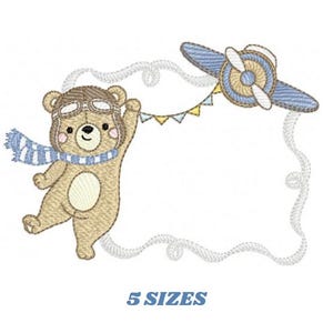 May include: Embroidered design of a brown bear wearing a pilot's hat and scarf, holding a string of flags attached to a blue airplane. The design is set within a white cloud-shaped frame.