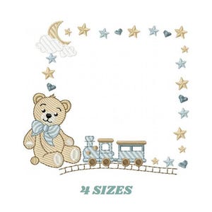 May include: An embroidered design featuring a teddy bear with a blue bow, a train, and a border of stars, hearts, and a crescent moon. The text "4 SIZES" is at the bottom. The design is in shades of beige, blue, and gold.