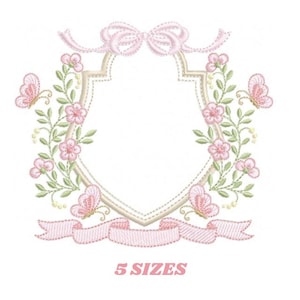 May include: Embroidered design featuring a pink floral wreath with butterflies surrounding a blank shield shape with a pink ribbon and bow at the top. The text "5 SIZES" is below the design.