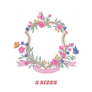 Może przedstawiać: Wzór haftu przedstawiający wieniec kwiatowy z różową wstążką i pustym tarczą w środku. Wieniec składa się z różowych, niebieskich i pomarańczowych kwiatów i liści. Wzór dostępny jest w 5 rozmiarach.