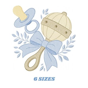 以下が含まれることがあります： ベージュとブルーの色合いのガラガラ、おしゃぶり、リボンの刺繍デザイン。葉のアクセント付き。「6 SIZES」の文字が下に表示されています。