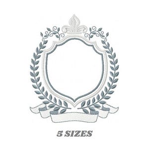 May include: A silver and gray embroidered design of a heraldic shield with a crown, surrounded by a wreath of leaves and a banner.
