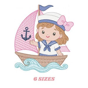 Puede incluir: Diseño bordado de una niña marinera de dibujos animados en un barco con una vela rosa y un ancla. La niña lleva un gorro de marinero con un lazo rosa y un atuendo de marinero azul y blanco. El texto "6 SIZES" está debajo.