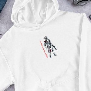 May include: White hooded sweatshirt with a black and white illustration of a character in a helmet and armor. The text "Always a soldier, never a hero" is printed in red on the right side of the image.