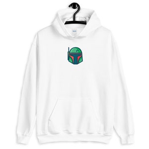 以下が含まれることがあります： 前面に緑、赤、青の漫画のヘルメットのデザインが施された白いフード付きスウェットシャツです。