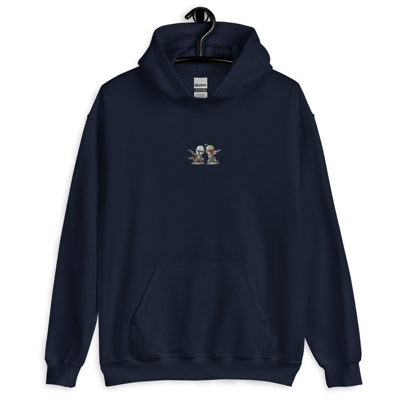 May include: A navy blue hoodie featuring a small embroidered image of two cartoon characters wearing helmets and holding weapons. The characters are standing side-by-side and appear to be in a playful pose.