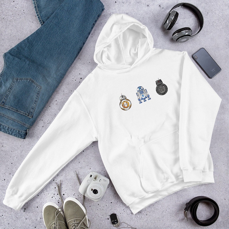 Puede incluir: Sudadera con capucha blanca con un estampado gr&aacute;fico de tres personajes de Star Wars: R2-D2, BB-8 y un caza TIE. Los personajes est&aacute;n en fila, con R2-D2 a la izquierda, BB-8 en el centro y el caza TIE a la derecha.