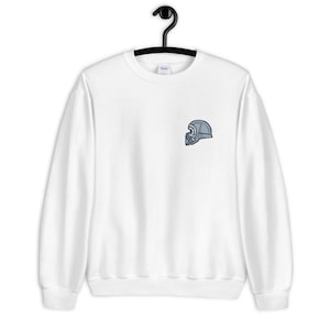 Może przedstawiać: Biała bluza z małym, haftowanym szarym wzorem hełmu na lewej piersi.