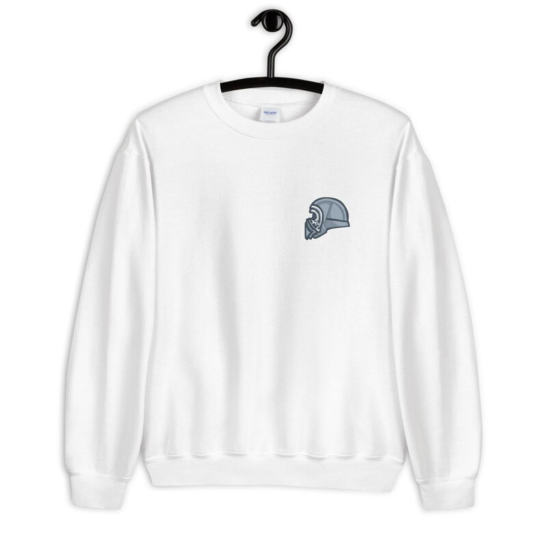 Może przedstawiać: Biała bluza z małym, haftowanym szarym wzorem hełmu na lewej piersi.