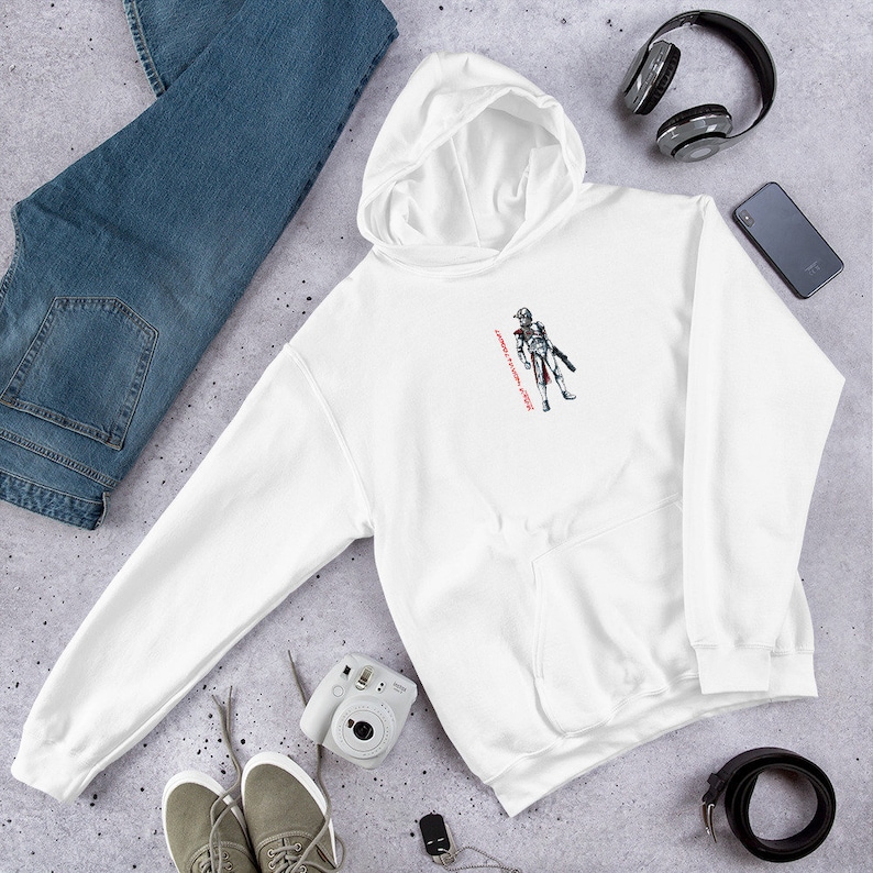 May include: White hooded sweatshirt with a black and white illustration of a character in a helmet and armor. The text "Always a soldier, never a hero" is printed in red on the right side of the image.