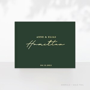 May include: Emerald green hardcover photo album with gold foil lettering. The album says "Anne & Elias Hamilton" and "04.12.2021".