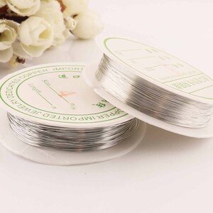 May include: Two spools of silver-coloured wire for jewellery making. The spools are labelled "Dedicated Copper Import Jewellery".