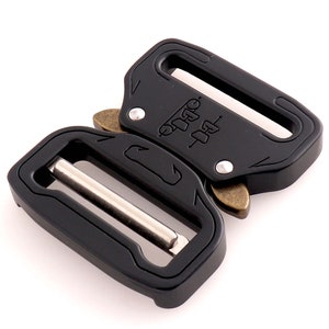 May include: Black metal buckle with a silver slider and brass accents. The buckle has the text "OUTDOOR" and "1-1/2" engraved on it.