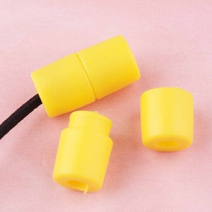 May include: Three yellow plastic cord end stoppers. Two of the stoppers are connected to a black cord.