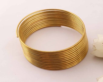 Pode incluir: Um bracelete de metal dourado feito de vários fios finos enrolados uns nos outros.