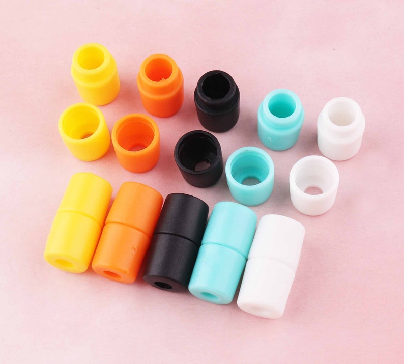 May include: Assortment of colorful plastic cord stoppers in various colors, including yellow, orange, black, white, and blue. The stoppers are designed to secure cords and cables.