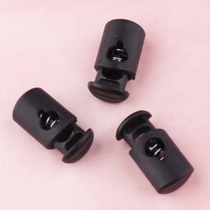 May include: Three black plastic cord locks with a spring mechanism. The cord locks are used for adjusting the length of cords or straps.