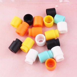 May include: Assortment of colorful plastic end caps in various colors, including black, white, yellow, orange, and blue. The end caps are small and round, with a hole in the center.
