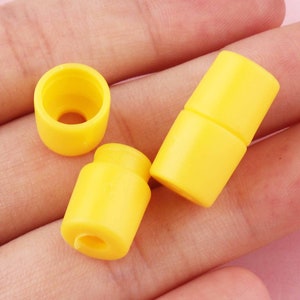 May include: Three yellow plastic cord end stoppers. The stoppers are cylindrical in shape with a small hole in the center.