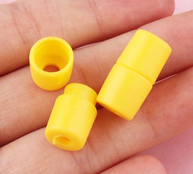 May include: Three yellow plastic cord end stoppers. The stoppers are cylindrical in shape with a small hole in the center.