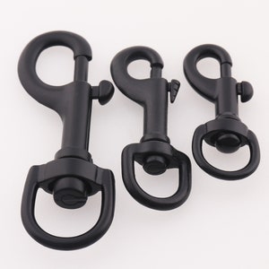 Puede incluir: Tres mosquetones giratorios de metal negro de diferentes tamaños. Los mosquetones están hechos de metal duradero y tienen un acabado liso y pulido.