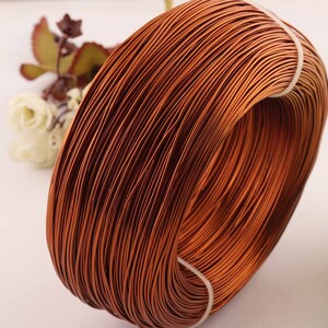 May include: A close-up of a spool of copper wire. The wire is wound tightly and has a reddish-brown color.