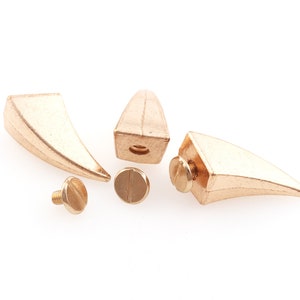 May include: Four gold-colored metal spikes with screw-on bases. The spikes are pointed and have a triangular shape. The screws are included.