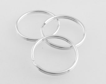 May include: Three silver key rings, each with a circular shape and a smooth, polished finish.
