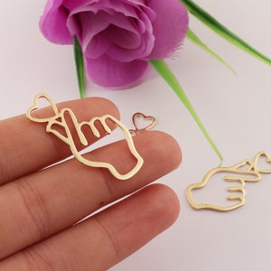 Op de afbeelding: Twee gouden metalen bedels in de vorm van een hand die een pinkbelofte doet met een hart. De bedels zijn perfect voor het maken van sieraden of knutselen.