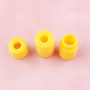 May include: Three yellow rubber stoppers of different sizes. The stoppers are round with a hole in the center.