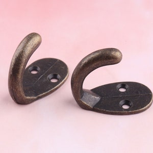 Peut inclure: Deux crochets en bronze antique avec des bases ovales. Chaque crochet a deux petits trous pour le montage.
