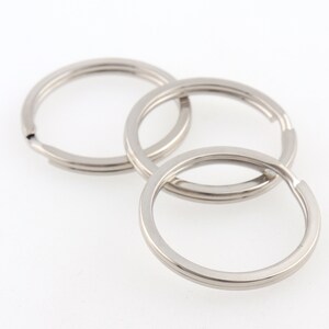 May include: Three silver key rings, each with a circular shape, are stacked on top of each other.