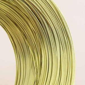 Könnte beinhalten: Nahaufnahme einer Rolle goldfarbenen Drahtes. Der Draht ist eng in einer Spule gewickelt und erzeugt ein Muster aus konzentrischen Kreisen.