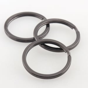 May include: Three black metal key rings. The key rings are stacked on top of each other.