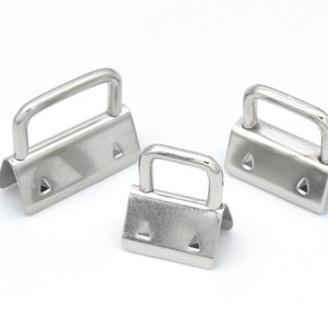 May include: Three silver metal D-ring clasps of different sizes. The clasps have a triangular base and a D-shaped ring.