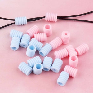Puede incluir: Surtido de tapones de cordón de silicona rosa y azul. Los tapones son acanalados y tienen un agujero en el centro.
